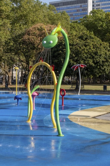 Large green dragon water play equipment with tower block in the background, Cologne, North Rhine-Westphalia, Germany