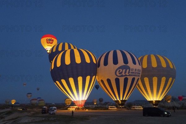 Several illuminated hot-air balloons decorate the sky at dawn, Göreme National Park, Göreme Tarihî Millî Parki, Nevsehir Province, Nevsehir, Cappadocia, Cappadocia, Cappadocia, Cappadocia, Central Anatolia, Turkey