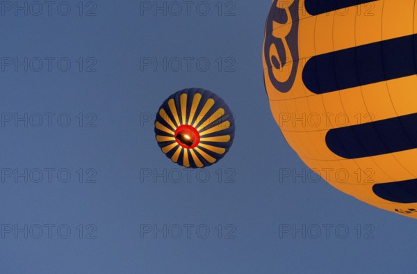 Two yellow-blue hot air balloons floating in front of a clear blue sky, Göreme National Park, Göreme Tarihî Millî Parki, Nevsehir Province, Nevsehir, Cappadocia, Cappadocia, Cappadocia, Cappadocia, Central Anatolia, Turkey