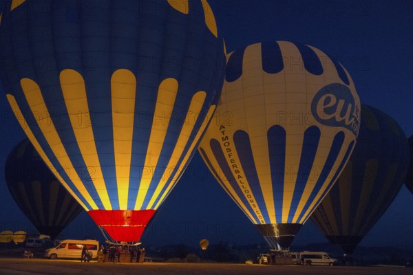 Illuminated hot air balloons glow in the dark, surrounded by a tranquil landscape, Göreme National Park, Göreme Tarihî Millî Parki, Nevsehir Province, Nevsehir, Cappadocia, Cappadocia, Cappadocia, Cappadocia, Central Anatolia, Turkey