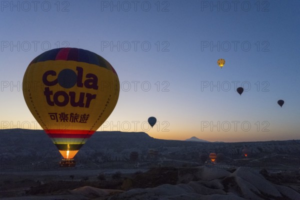 A balloon floats calmly at sunrise with the silhouetted landscape in the background, Göreme National Park, Göreme Tarihî Millî Parki, Nevsehir Province, Nevsehir, Cappadocia, Cappadocia, Kapadokya, Cappadocia, Central Anatolia, Turkey
