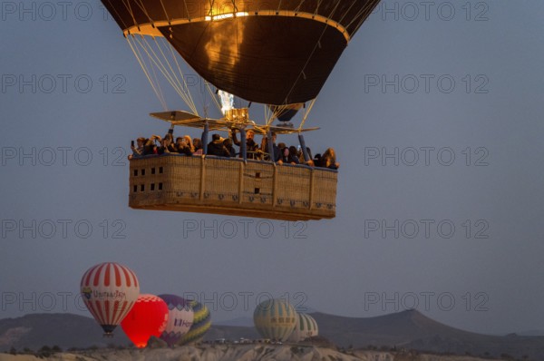 A hot air balloon with passengers in the basket floats under the morning sky, Göreme National Park, Göreme Tarihî Millî Parki, Nevsehir Province, Nevsehir, Cappadocia, Cappadocia, Kapadokya, Cappadocia, Central Anatolia, Turkey