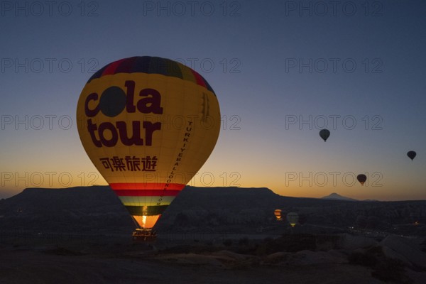 A colourful hot air balloon rises into the quiet sky at sunrise, Göreme National Park, Göreme Tarihî Millî Parki, Nevsehir Province, Nevsehir, Cappadocia, Cappadocia, Cappadocia, Cappadocia, Central Anatolia, Turkey