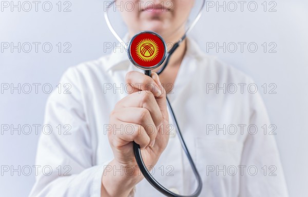Female doctor holding stethoscope with Kyrgyzstan flag. National health system of Kyrgyzstan