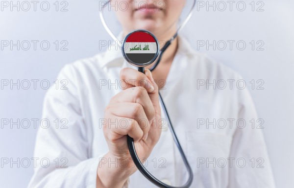 Female doctor holding stethoscope with Iraq flag. National health system of Iraq