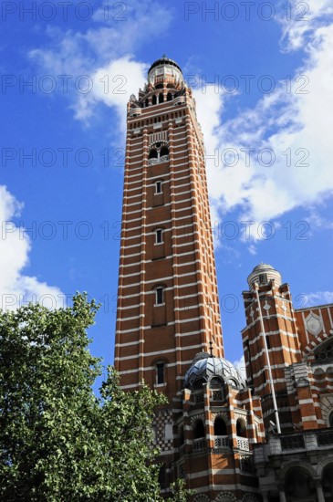Partial view Westminster Cathedral, London, England, Great Britain, Europe, High red spire against blue sky and green trees, London region