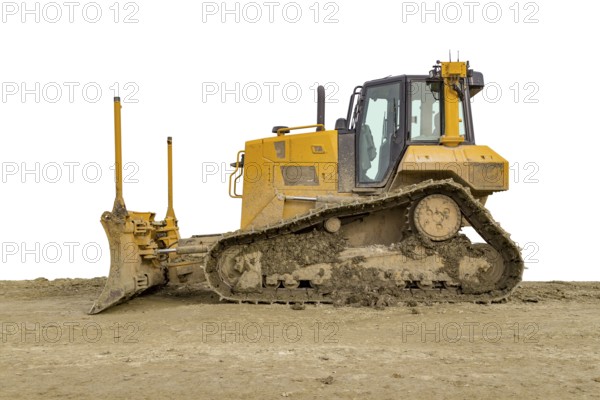 Yellow bulldozer at a loamy construction site, partly isolated in white back