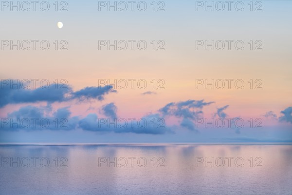 Ocean scenery including some clouds and the moon at evening time