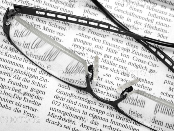 Newspaper detail with pair of glasses