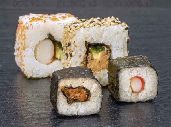 Various sushi dishes on dark grey stone surface