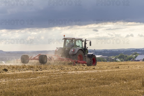 Tractor on a stubble field in stormy ambiance