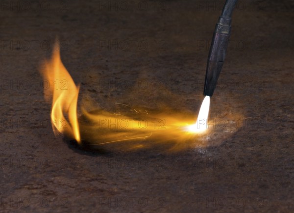 Welding torch tip and dashing flame on rusty metallic ground