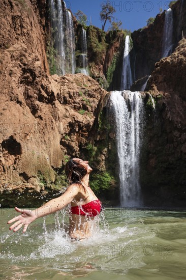 Beautiful woman bathing under a waterfall Ouzoud in Morocco