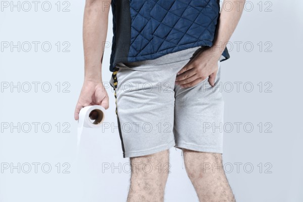 Man with diarrhea holding toilet paper an his anus