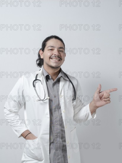 Smiling young doctor pointing to the right on isolated