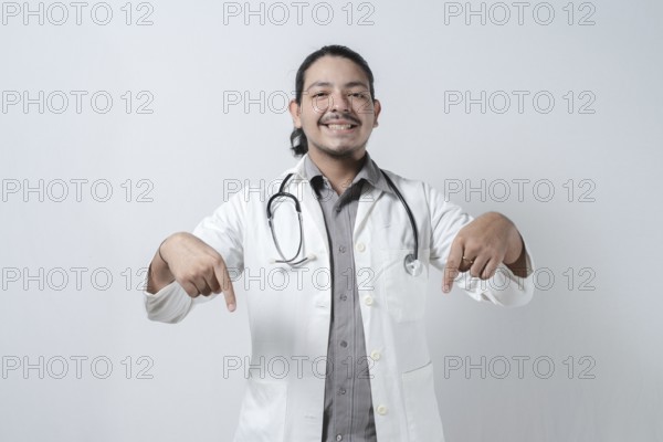 Smiling doctor pointing down isolated. Young latin doctor pointing down isolated