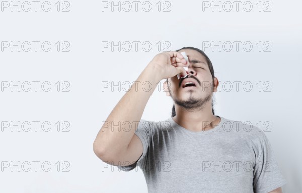 Young man with nosebleed on isolated background. Person with sinusitis or epistaxis. Concept of a person with a nosebleed