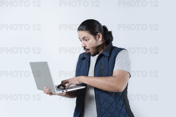 Man surprised looking at the computer he is holding on isolated