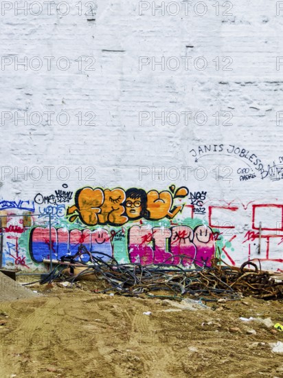 Colourful graffiti adorns a white wall above a rough floor with scattered cables Mariahilferstrasse Vienna Austria