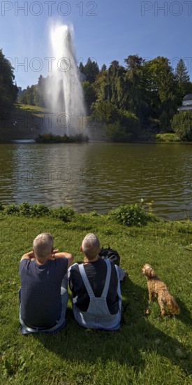 Couple with dog at the water games at the big pond with the high rising fountain, Bergpark Wilhelmshöhe, UNESCO World Heritage Site, Kassel, Hesse, Germany