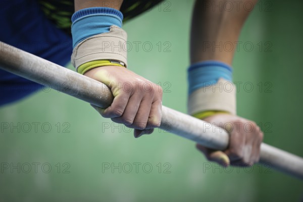 Close up of a gymnastics athlete gripping a sports bar with white chalk on their hands, AI generated