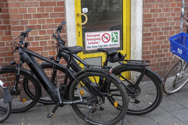 Bicycle traffic in Münster, bicycles parked on the pavement, in front of an emergency exit, which is also labelled as such, North Rhine-Westphalia, Germany
