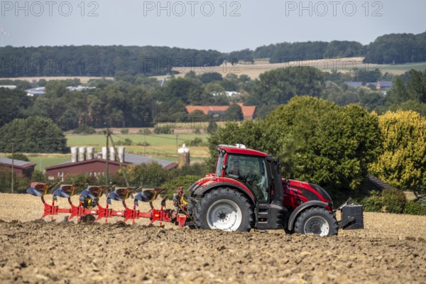 Tractor ploughs up a harvested grain field, south of Billerbeck in Münsterland, North Rhine-Westphalia, Germany