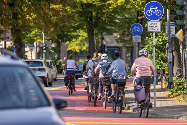 Cycle traffic in Münster, Warendorf Straße, broadly marked red asphalt as cycle path, cycle lane, colour-coded separated from the lane for cars, city centre of Münster, North Rhine-Westphalia, Germany