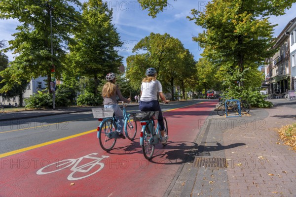 Cycle traffic in Münster, Warendorf Straße, broadly marked red asphalt as cycle path, cycle lane, colour-coded separated from the lane for cars, city centre of Münster, North Rhine-Westphalia, Germany