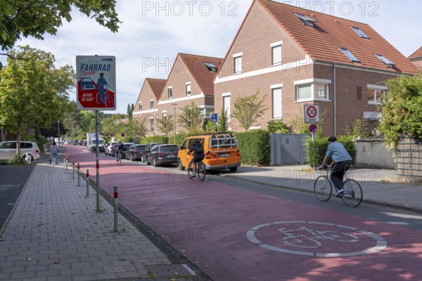 Cycling in Münster, cycle lane, Goldstraße, red asphalt and pictograms indicate to motorists that cyclists have priority, city centre of Münster, North Rhine-Westphalia, Germany