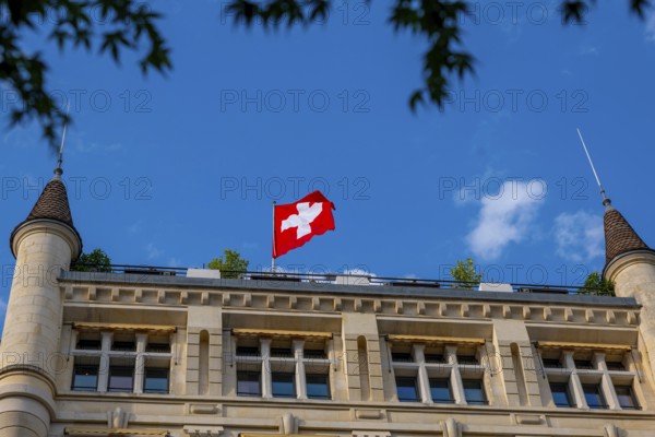 Beautiful Swiss Flag on a Old Building with Towers Against Blue Sky in a Sunny Summer Day in Lausanne, Vaud, Switzerland