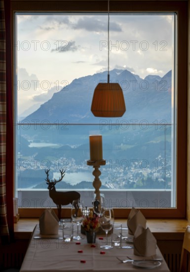Beautiful Restaurant Table Window View over Alpine Lake and Swiss Alps and Cityscape in Sunset and Clouds over St Moritz, Maloja, Grisons, Switzerland