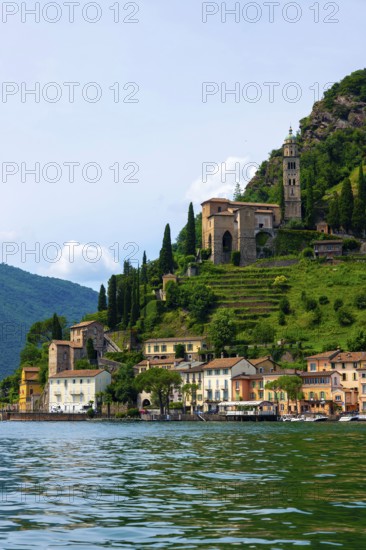 House and Church on Mountain Range in a Sunny Summer Day on the Waterfront to Lake Lugano in Morcote, Lugano, Ticino, Switzerland