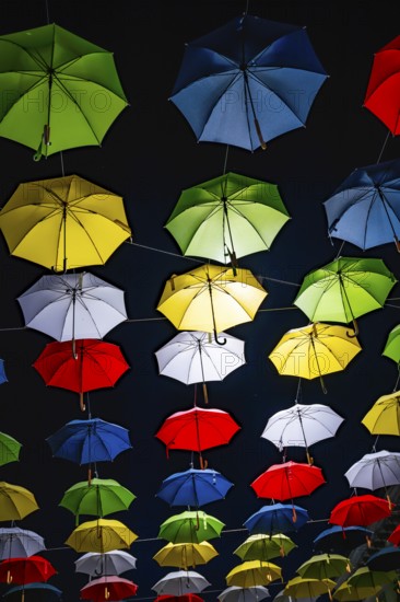 Many Illuminated Colorful Umbrellas Hanging Against Sky at Night in Switzerland
