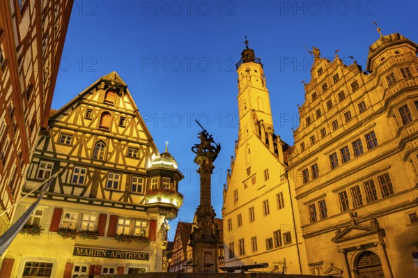 Georgsbrunnen, Marien-Apotheke, town hall and town hall tower in Rothenburg ob der Tauber at dusk, Bavaria, Germany
