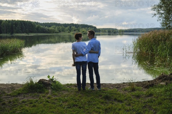 Couple enjoying a serene moment by the lake during golden hour at a tranquil nature spot