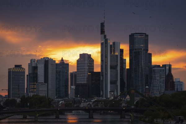 The sun breaks through the clouds behind the Frankfurt banking skyline shortly in front of setting, Frankfurt am Main, Hesse, Germany