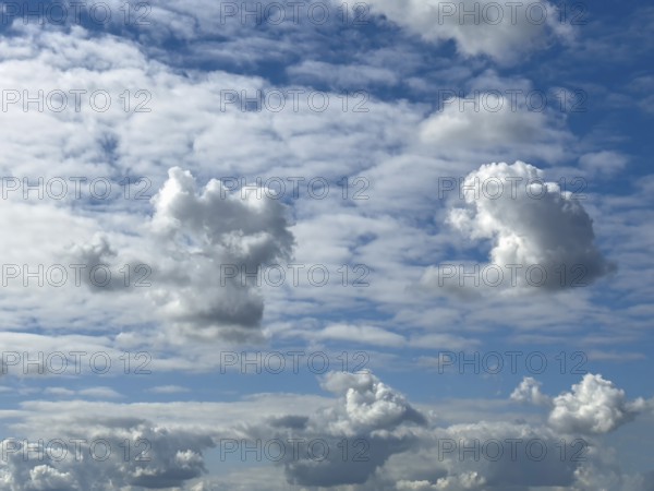 Several types of cumulus white clouds, cumulus clouds at the bottom edge of the picture, cumulus clouds piling up in the centre of the picture, cumulonimbus above it, many cirrocumulus clouds behind it, international