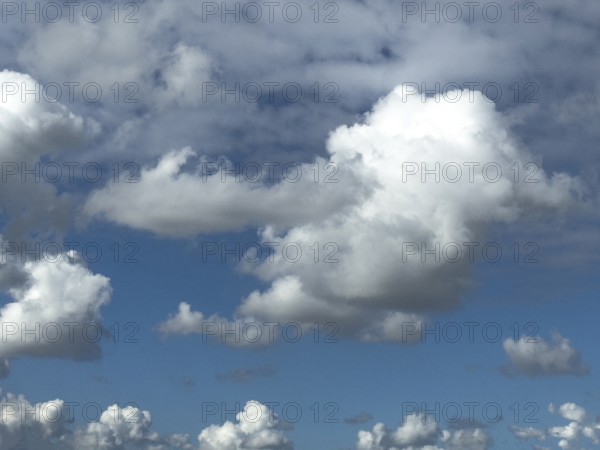 Cumulus clouds at the bottom edge of the image, large white cumulonimbus cluster cloud towering in the centre of the image, altocumulus above, international