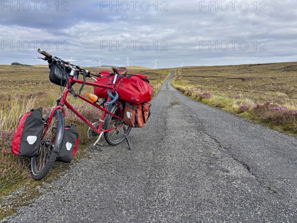A fully loaded bicycle stands on a long country road in a wide landscape, Adventure, Cycling tour, Isle of Lewis Hebrides, Scotland, Great Britain
