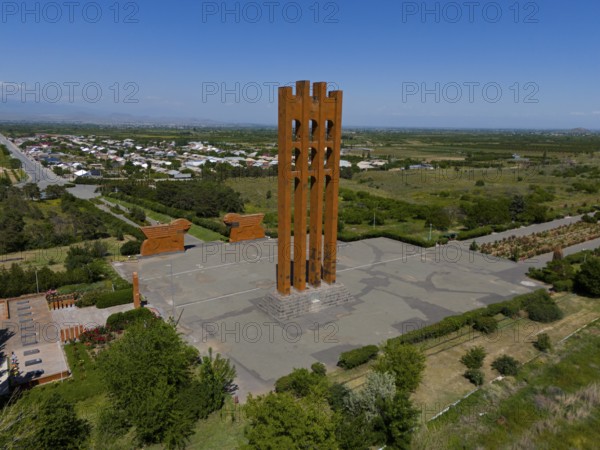 Large modern monument surrounded by landscape and small buildings under blue sky, aerial view, Sardarapat monument, Araks village, Armavir province, Armenia