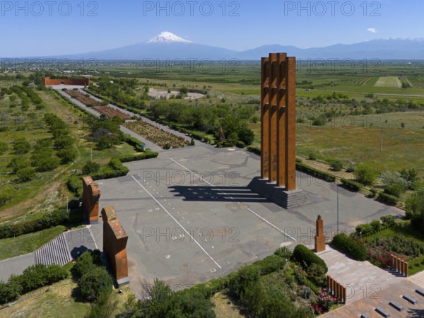 Large modern monument in front of a mountain panorama under a clear blue sky, aerial view, Sardarapat monument, Araks village, Armavir province, in the background Mount Ararat in Turkey, Armenia