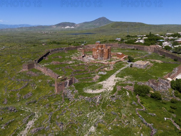Expansive view of a historic fortress with surrounding stone walls in a green mountain landscape, Dashtadem Fortress, Qagheni Fortress, Dashtadem village, Aragatsotn Province, Armenia