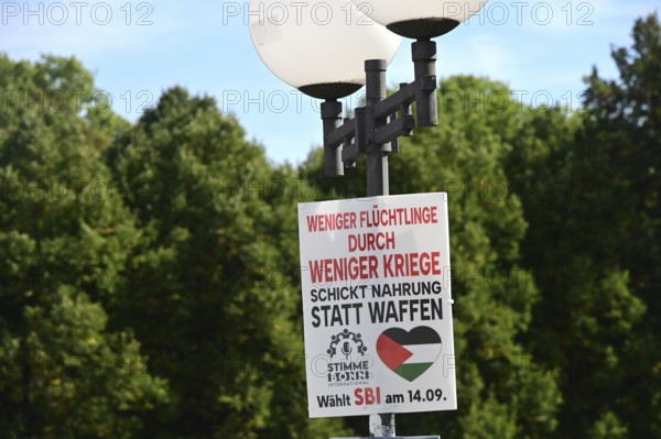 Posters for the North Rhine-Westphalia municipal election campaign in Bonn around the Hofgarten in the university district. Poster of the Stimme Bonn International (SBI) party calling for fewer refugees through fewer wars - send food instead of weapons