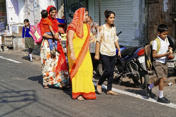 Udaipur, Rajasthan, North India, Asia, Women in colourful saris and children walking along a busy street