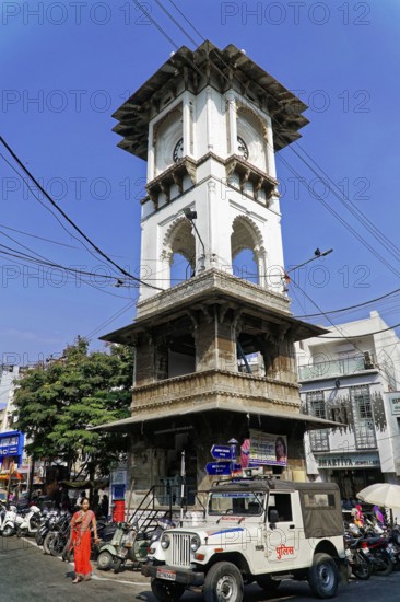 Udaipur, Rajasthan, North India, Asia, Historic tower in an urban setting under a clear sky, surrounded by everyday life