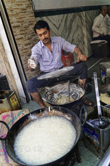 Udaipur, Rajasthan, North India, Asia, Man cooking a traditional dish on the street with pans and oil on an open fire