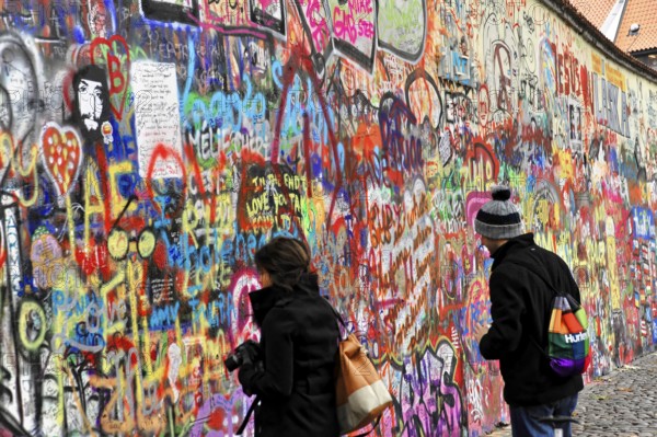 John Lennon Wall, Graffiti, Prague, Czech Republic, Europe, Two people look at a colourful wall full of graffiti and street art in the city