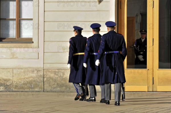 Changing of the guard at Prague Castle, Hradcany, Prague, Czech Republic, Europe, Three soldiers in uniform march towards a large wooden gate