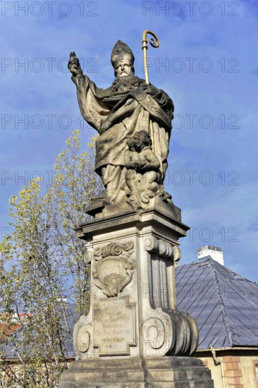 Statue on Charles Bridge, Old Town, UNESCO World Heritage Site, Prague, Czech Republic, Europe, Stone statue of a bishop with a child on an ornate pedestal against a blue sky